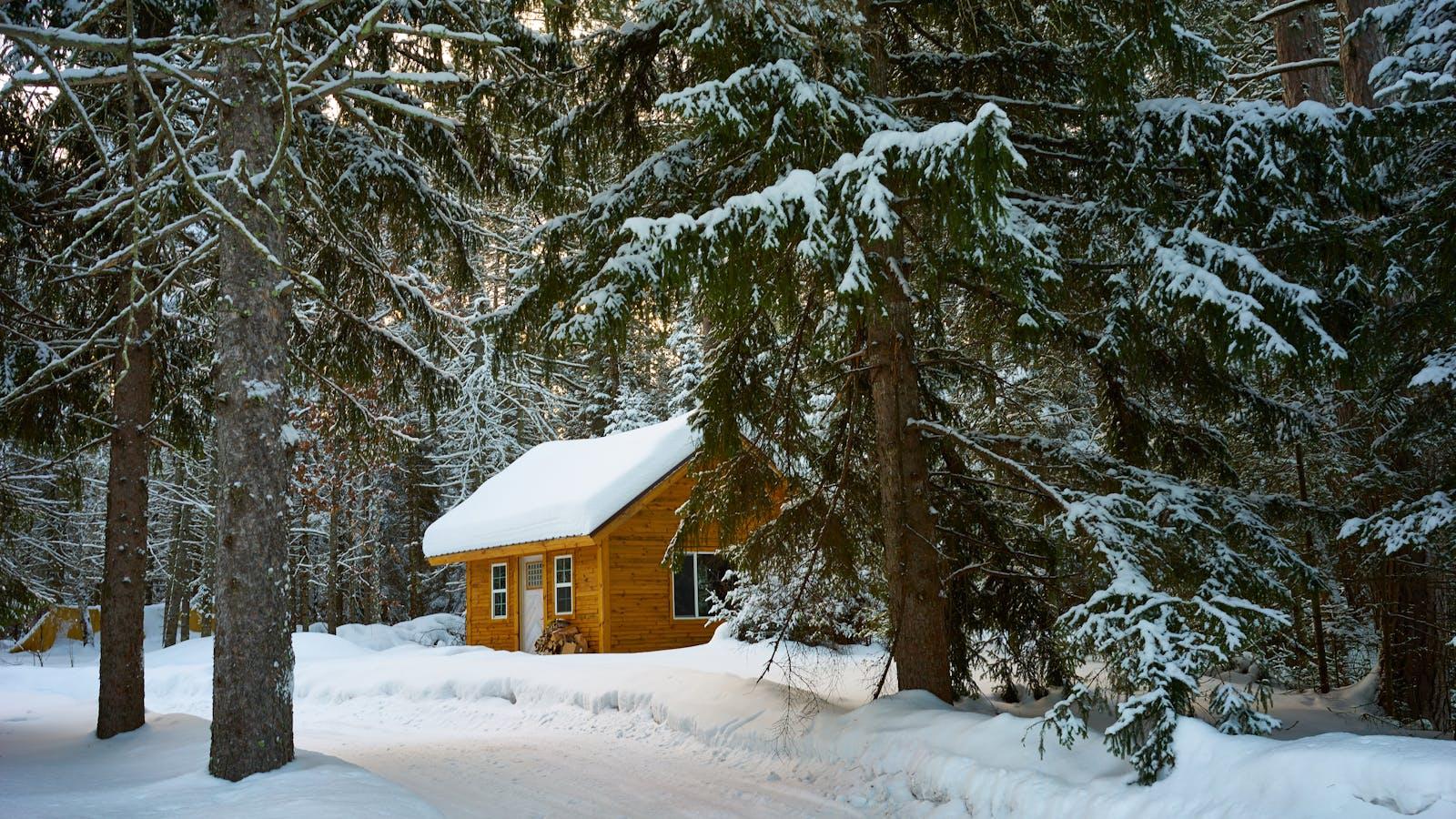Snow-covered Truckee mountain home with large windows and Sierra pine trees at golden hour